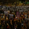 Protesters holding pictures of Hamas-Israel war hostages that read "bring them home"