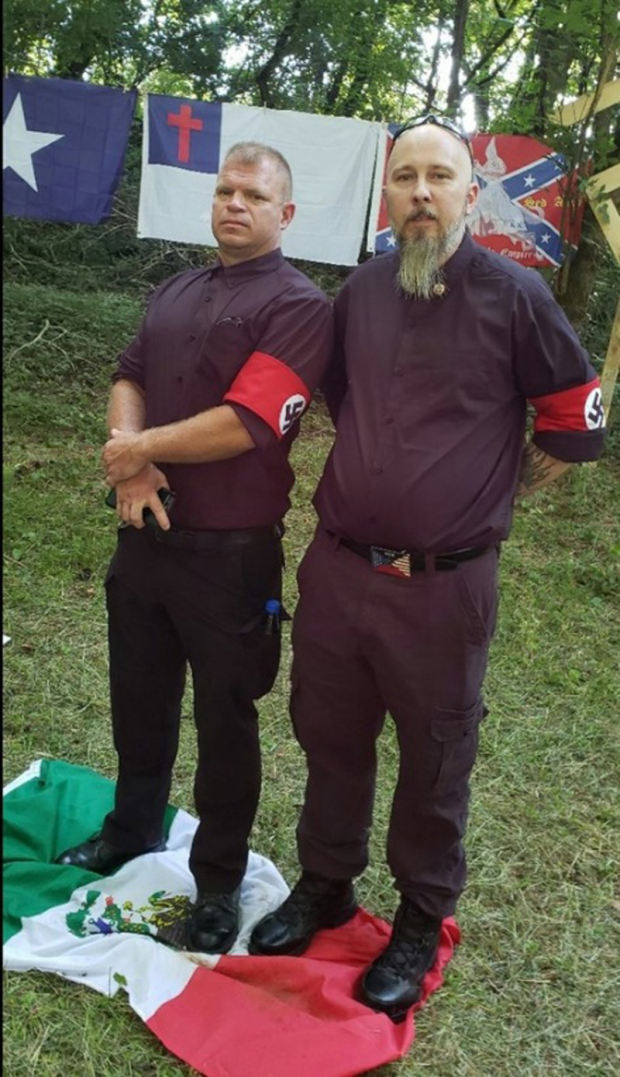 National Socialist Movement members stand on a Mexican flag during a private event